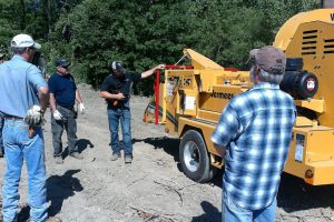 Four men with yellow wood chipper